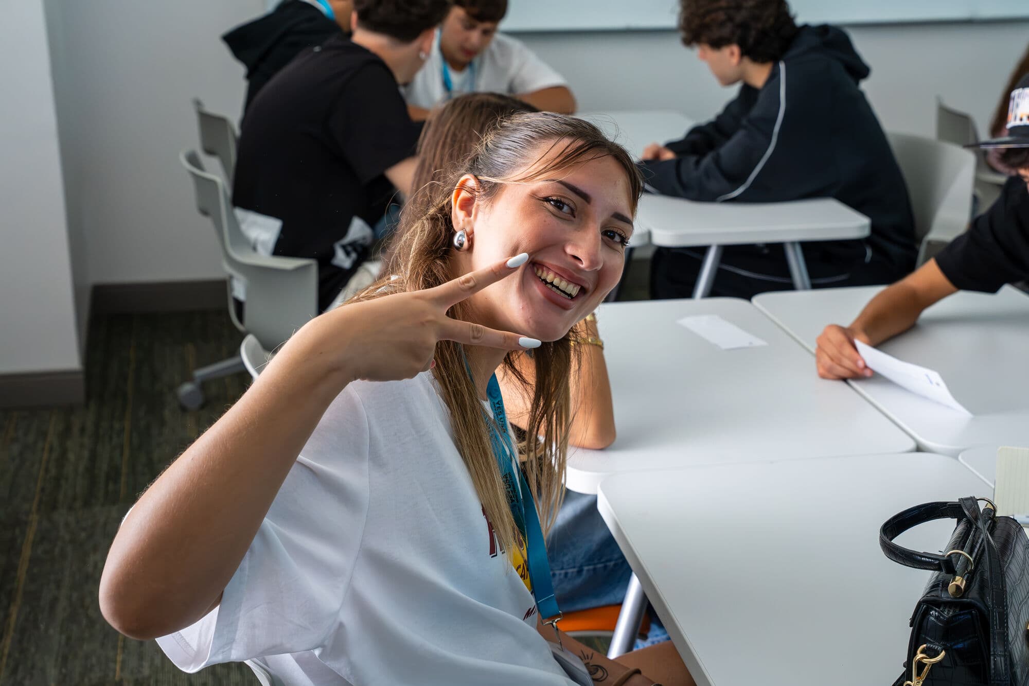 Aluna sorrindo e fazendo sinal de paz durante a aula