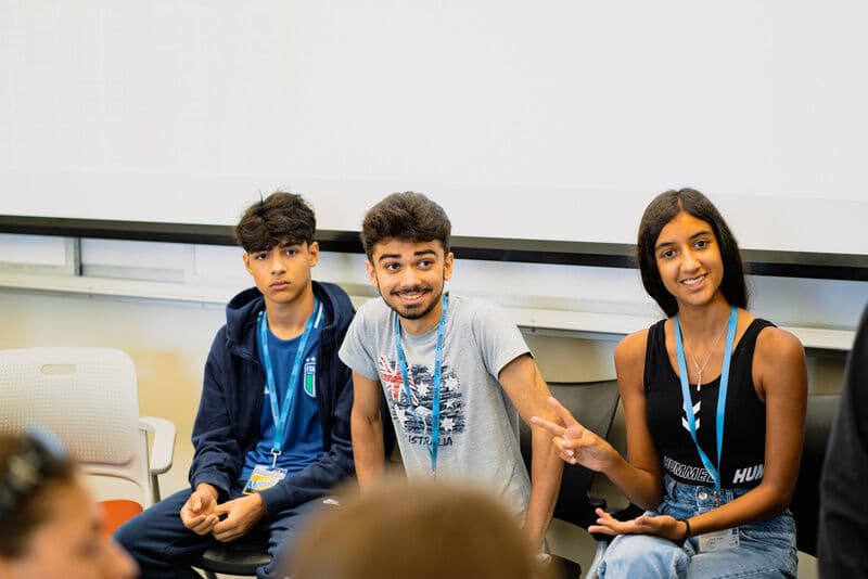 Três alunos rindo durante a aula de inglês