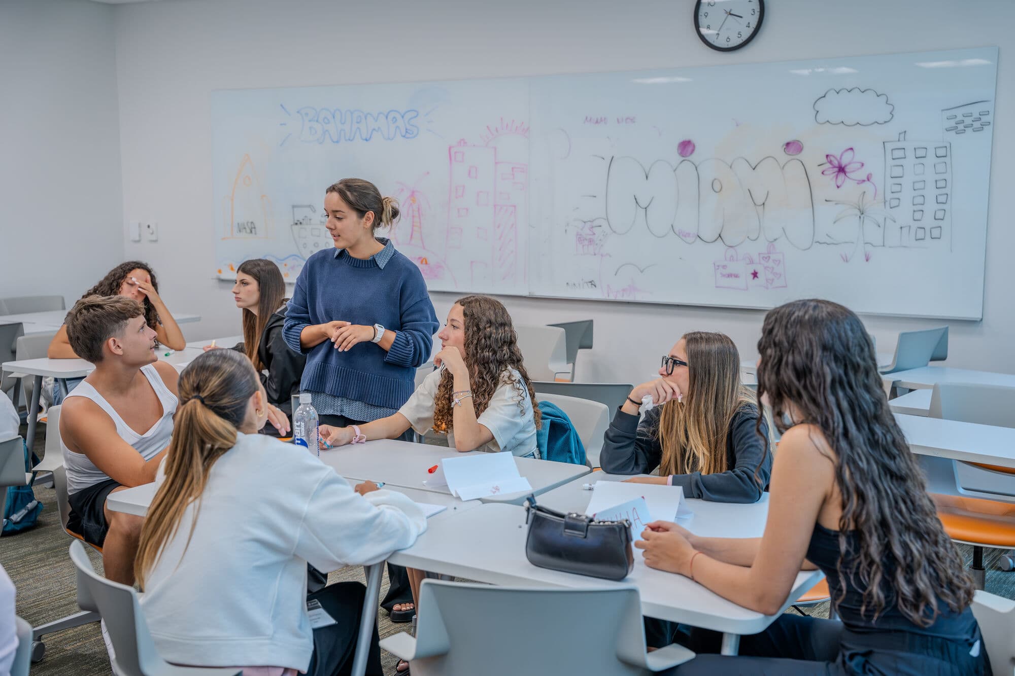Alunos trabalhando em grupo com a professora, com o projeto no quadro