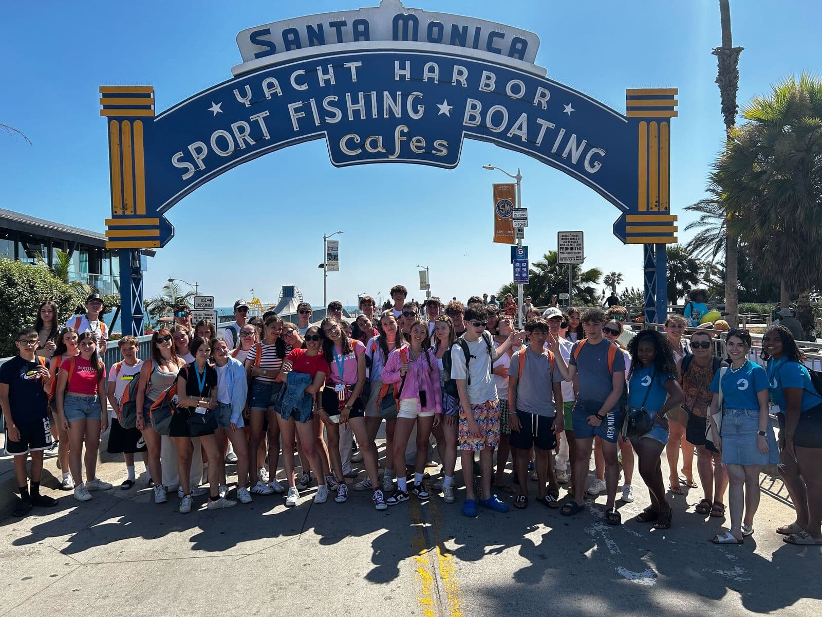 Grupo grande de alunos sob o letreiro do píer de Santa Monica