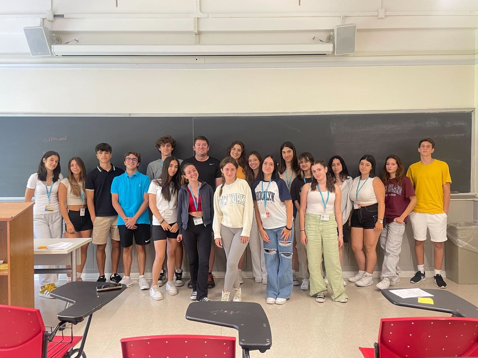Turma posando em frente ao quadro negro no campus em Queens