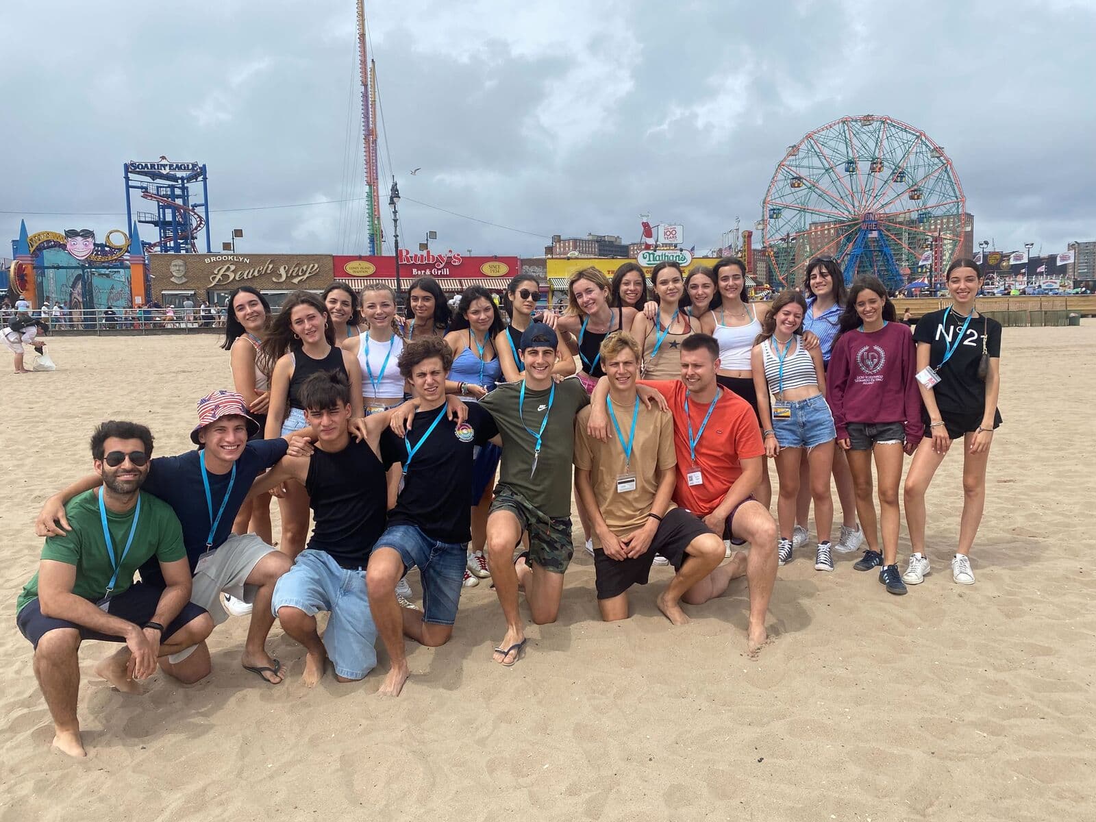 Grupo de alunos na praia de Coney Island, com a roda-gigante ao fundo