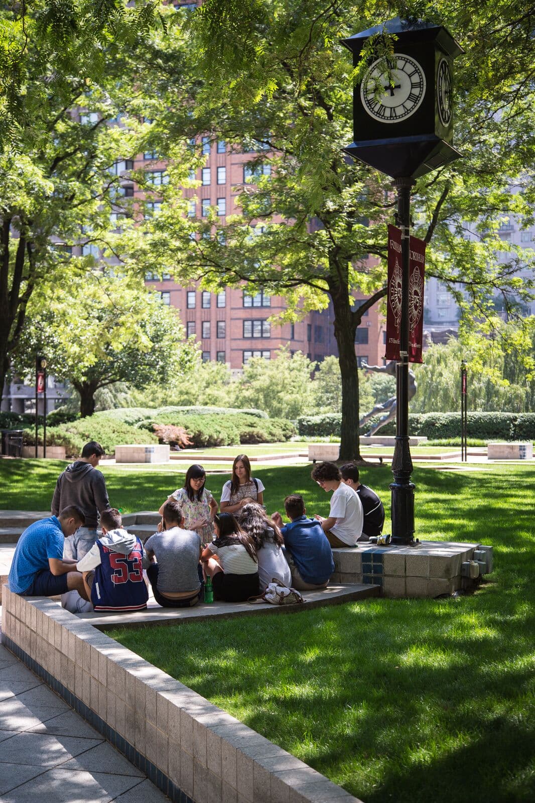 Alunos sentados no gramado do jardim do campus em Manhattan