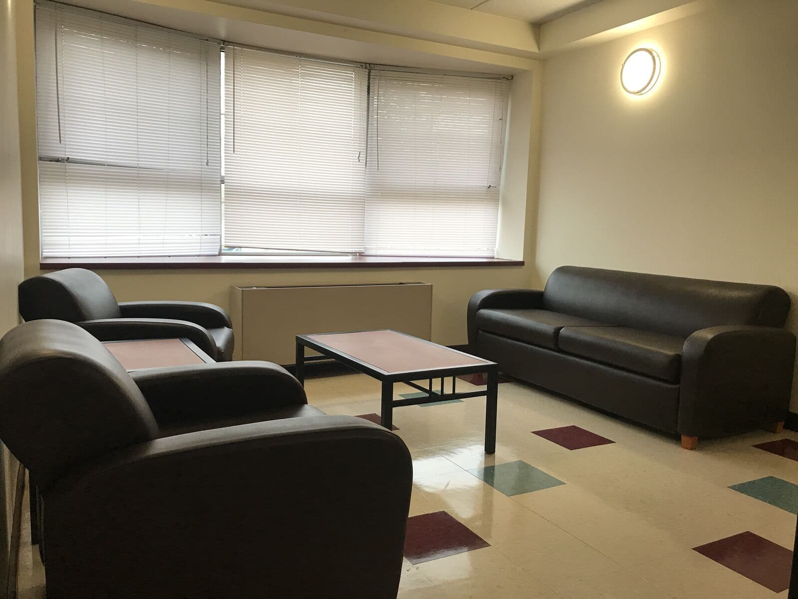 Sala da suíte na residência em Queens, com sofás e mesa de jantar